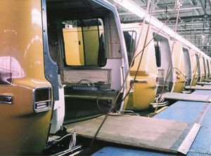 A line of motorhomes backed up to a raised platform, without their rear panels and with a ramp set into the interior for each coach.